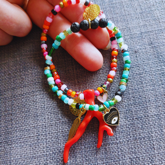 Armband in groen blauwe tinten samen met armband in rood roze tinten. Beide met diverse bedels