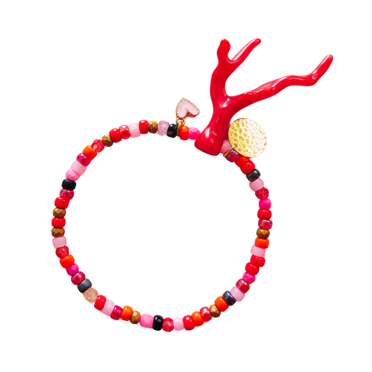 Armband in rode en roze rocailles met een rood koraal takje als eye-catcher